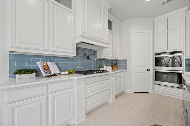 kitchen with light tile patterned floors, stainless steel appliances, glass insert cabinets, and white cabinets