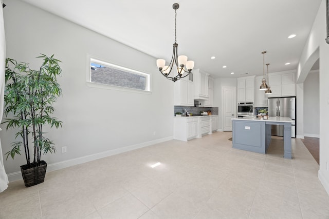 kitchen with pendant lighting, tasteful backsplash, stainless steel appliances, white cabinets, and light countertops