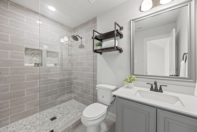 bathroom featuring vanity, toilet, and a tile shower