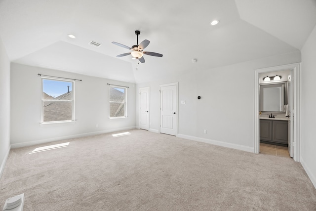 unfurnished bedroom with visible vents, baseboards, a sink, vaulted ceiling, and light colored carpet