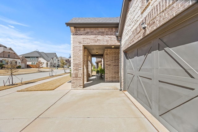 view of patio featuring a garage, a residential view, covered porch, and driveway