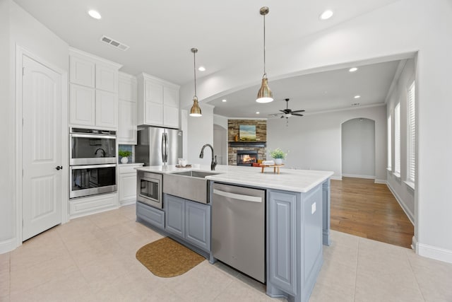 1109 Rendon Pl, Mansfield, TX 76063 - kitchen featuring appliances with stainless steel finishes, a ceiling fan, open floor plan, a fireplace, and gray cabinets