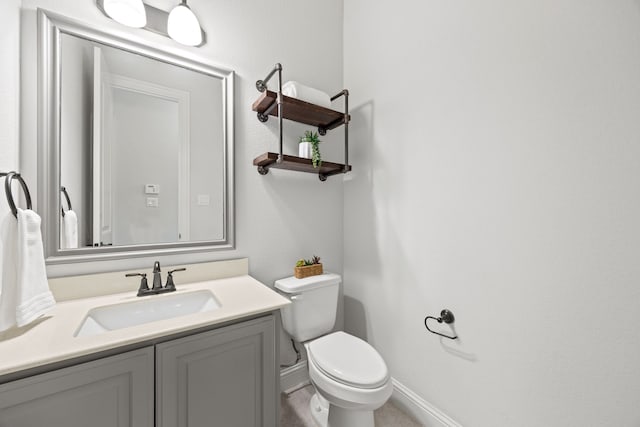 half bath with baseboards, toilet, and vanity