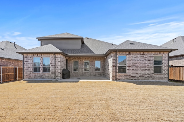 back of property with a fenced backyard, a lawn, and roof with shingles