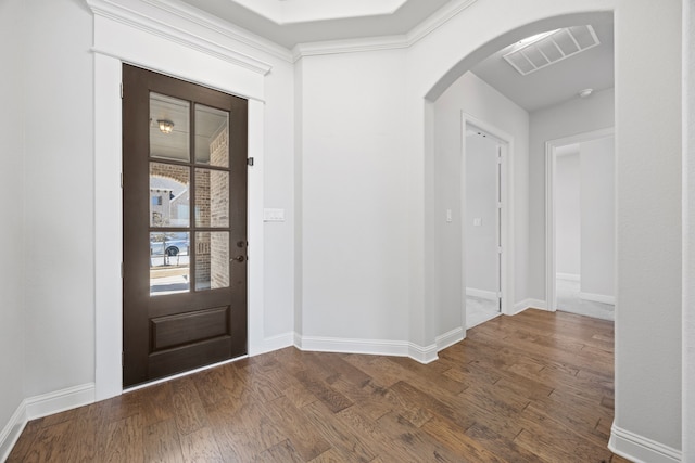 entrance foyer featuring dark wood-type flooring, visible vents, arched walkways, and baseboards