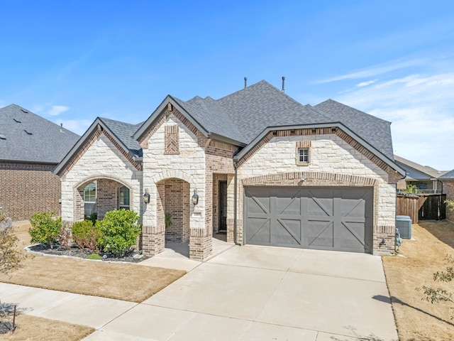 1109 Rendon Pl, Mansfield, TX 76063 - french country style house featuring stone siding, roof with shingles, an attached garage, driveway, and brick siding