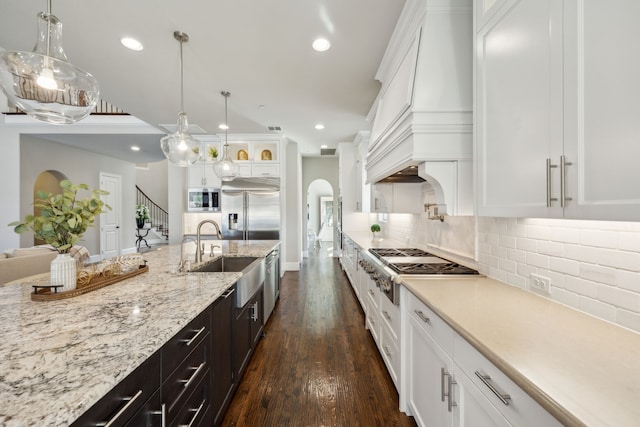 kitchen featuring white cabinets, built in appliances, and a sink