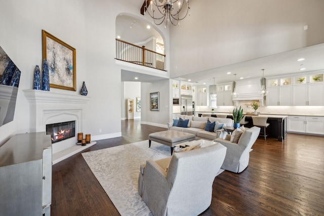 living area featuring baseboards, recessed lighting, a high ceiling, dark wood-style floors, and a glass covered fireplace