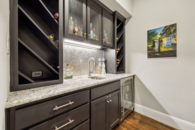 bar featuring dark wood-style floors, beverage cooler, a sink, indoor wet bar, and backsplash