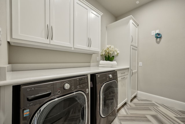 washroom with cabinet space, washing machine and dryer, and baseboards