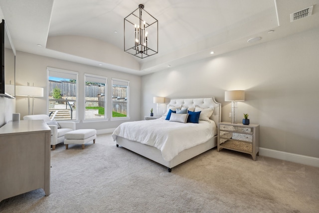 carpeted bedroom with visible vents, baseboards, lofted ceiling, a tray ceiling, and a notable chandelier