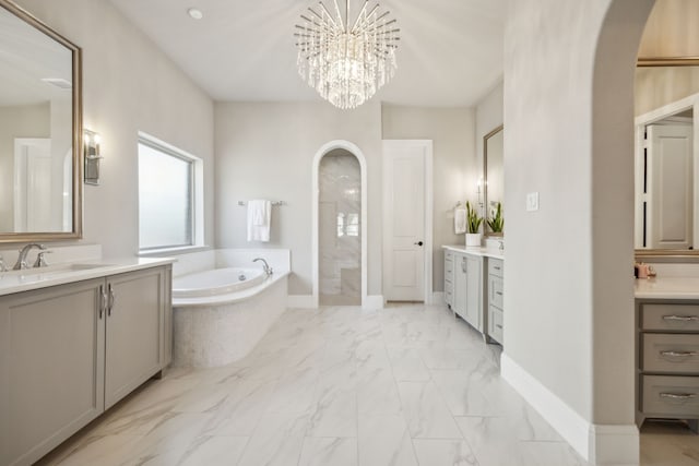 full bathroom featuring baseboards, two vanities, a sink, a bath, and marble finish floor