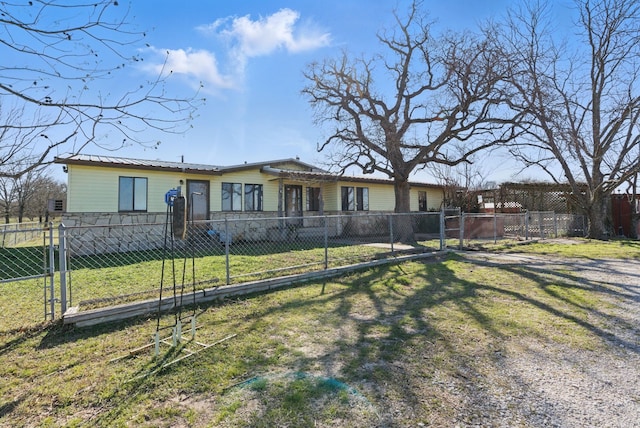 view of front of house with a fenced front yard, metal roof, a front yard, and a gate