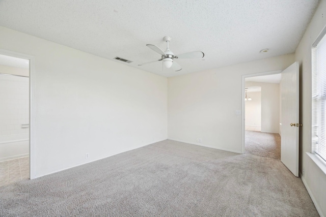 spare room with ceiling fan, carpet flooring, visible vents, and a textured ceiling