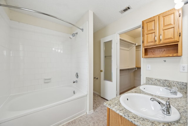 full bathroom featuring visible vents, double vanity, a sink, bathtub / shower combination, and a textured ceiling