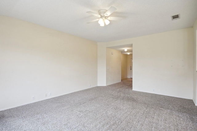 spare room featuring carpet, a ceiling fan, visible vents, and a textured ceiling