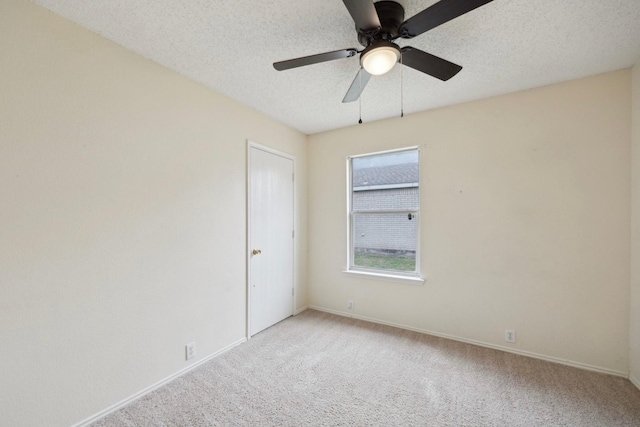 unfurnished room featuring baseboards, light colored carpet, ceiling fan, and a textured ceiling