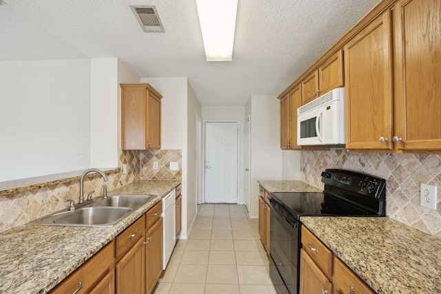 kitchen with visible vents, brown cabinets, light tile patterned flooring, white appliances, and a sink