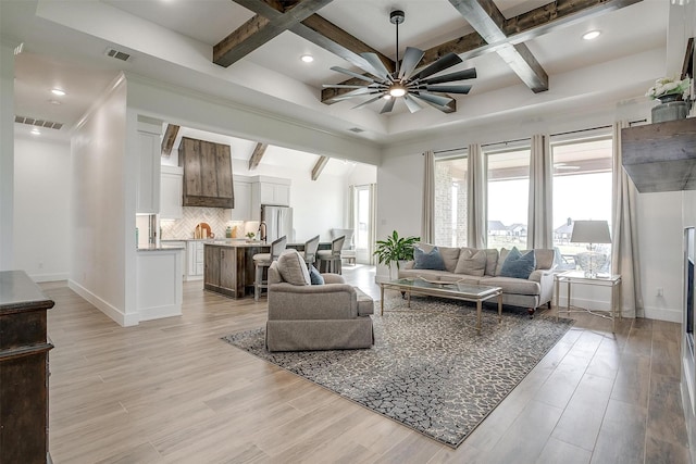 living area with light wood-style floors, visible vents, and baseboards