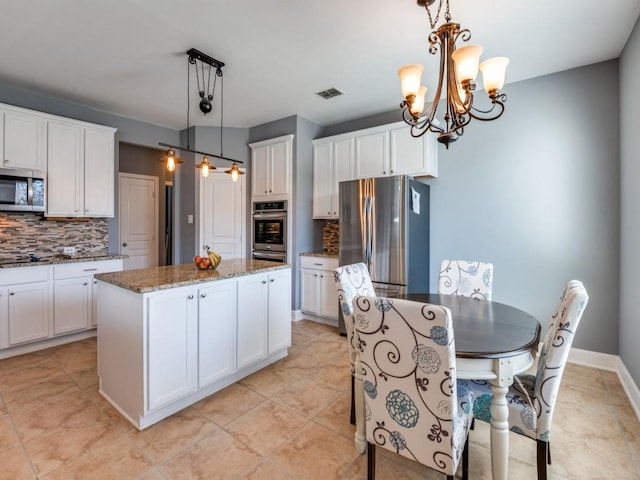 kitchen with dark stone countertops, visible vents, appliances with stainless steel finishes, white cabinetry, and a center island