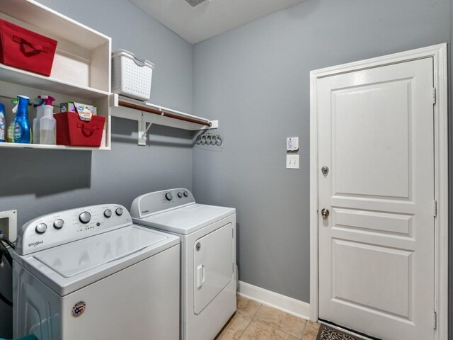 laundry area featuring light tile patterned floors, baseboards, laundry area, and washing machine and clothes dryer