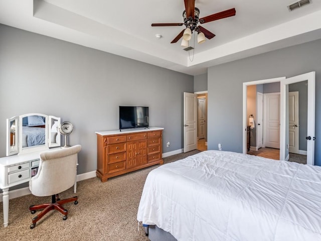 bedroom featuring a raised ceiling, baseboards, visible vents, and carpet floors