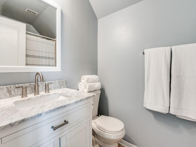 bathroom featuring visible vents, baseboards, toilet, lofted ceiling, and vanity