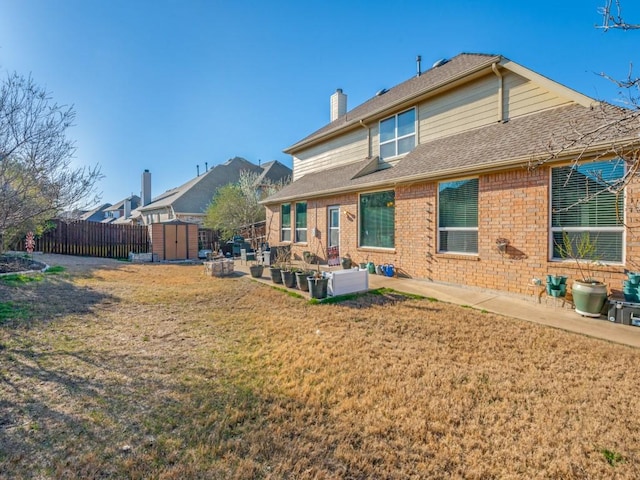 back of property with an outbuilding, fence, a shed, a chimney, and a patio area