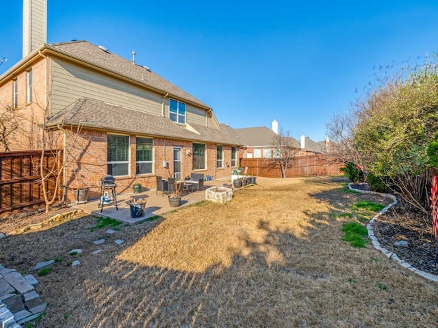 back of house with a patio, a yard, a fenced backyard, a chimney, and brick siding