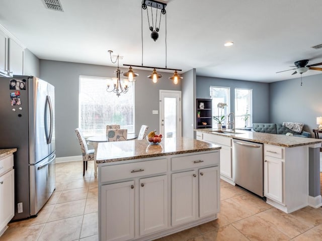 kitchen with visible vents, a kitchen island, stainless steel appliances, white cabinetry, and a sink