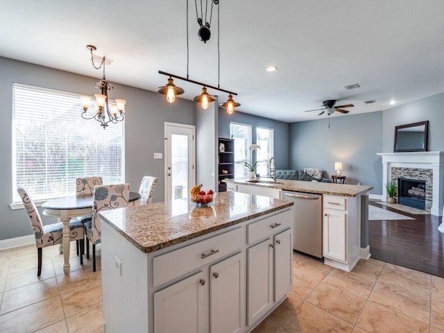 kitchen with a center island, open floor plan, a tile fireplace, stainless steel dishwasher, and a sink