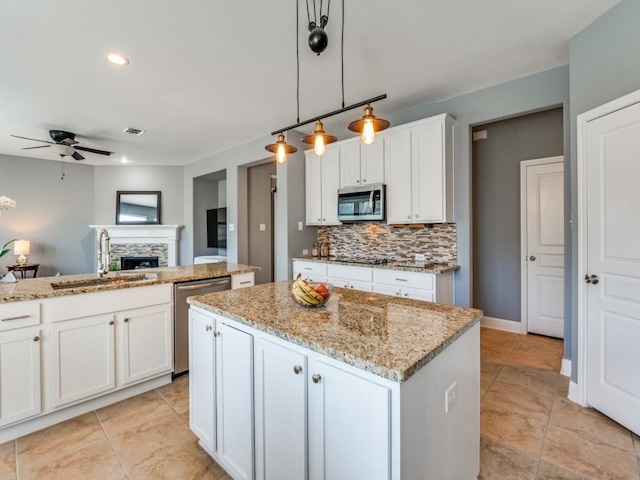 kitchen with a sink, a kitchen island, stainless steel appliances, a fireplace, and decorative backsplash