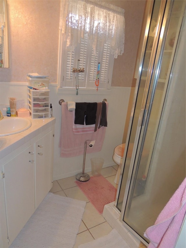 full bathroom featuring vanity, tile patterned flooring, a shower stall, wainscoting, and toilet