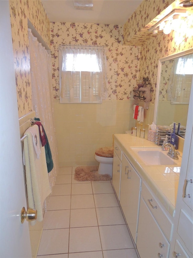 full bath featuring wallpapered walls, toilet, a wainscoted wall, and tile patterned flooring