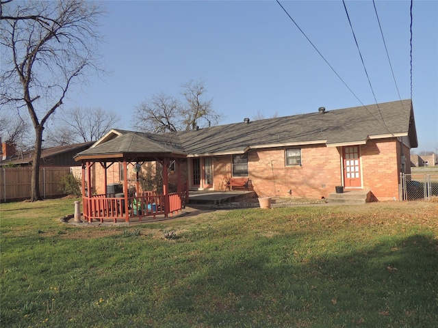 back of property featuring a gazebo, a lawn, brick siding, and fence