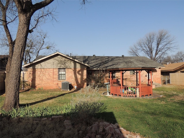 back of property featuring central air condition unit, a yard, fence, and brick siding