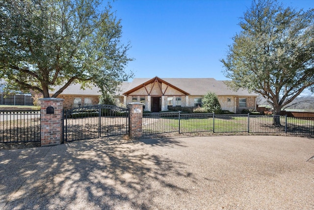 english style home featuring a gate, stone siding, and a fenced front yard