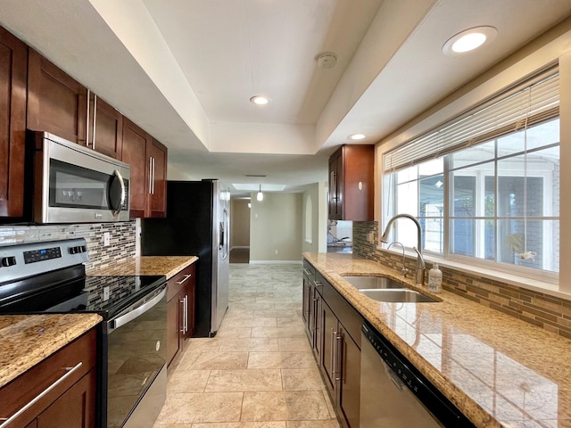 kitchen with baseboards, a sink, appliances with stainless steel finishes, a raised ceiling, and tasteful backsplash