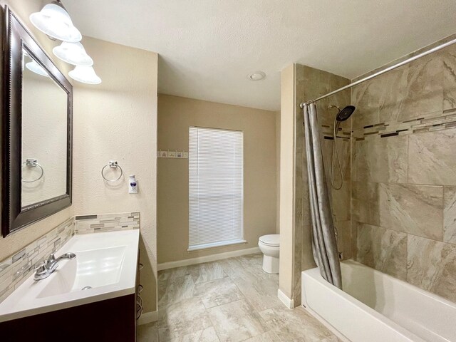 full bathroom with shower / bath combo with shower curtain, toilet, a textured ceiling, baseboards, and vanity