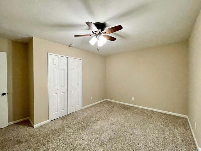 unfurnished bedroom with carpet, baseboards, a closet, and ceiling fan