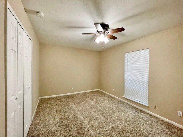 unfurnished bedroom with a closet, baseboards, a ceiling fan, and carpet flooring