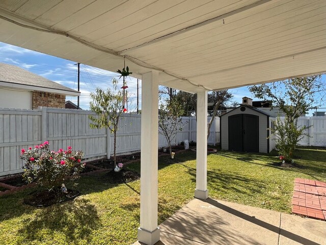 view of yard with a storage shed, a fenced backyard, an outbuilding, and a patio