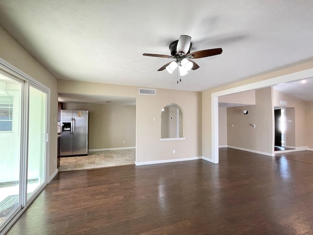 unfurnished living room with visible vents, ceiling fan, baseboards, wood finished floors, and a textured ceiling