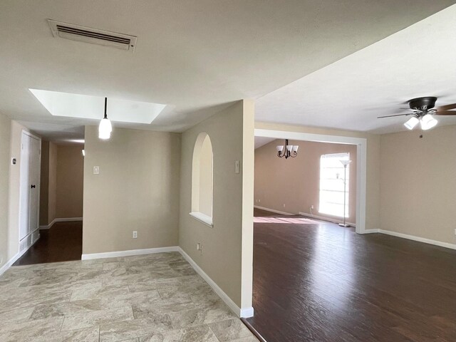 unfurnished room with visible vents, baseboards, and ceiling fan with notable chandelier