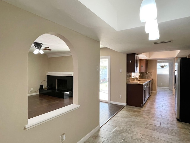 kitchen with visible vents, a fireplace with raised hearth, baseboards, decorative backsplash, and stainless steel fridge