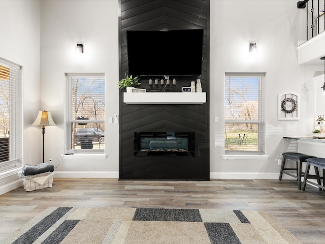 living area with baseboards, a towering ceiling, and wood finished floors