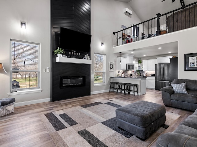 living room featuring a fireplace, light wood-style floors, baseboards, and a healthy amount of sunlight