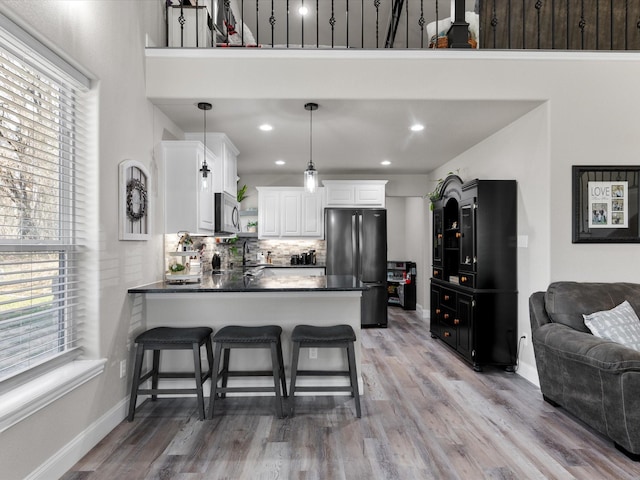 kitchen featuring dark countertops, stainless steel microwave, plenty of natural light, and freestanding refrigerator