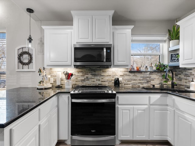 kitchen featuring pendant lighting, a sink, backsplash, white cabinetry, and appliances with stainless steel finishes