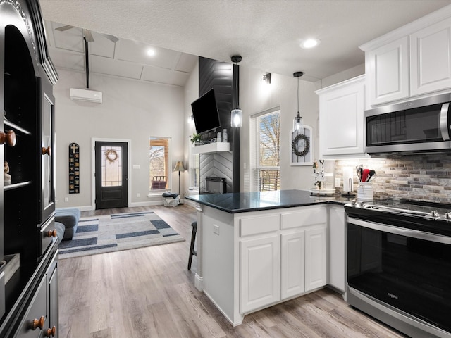 kitchen with dark countertops, tasteful backsplash, open floor plan, a peninsula, and stainless steel appliances